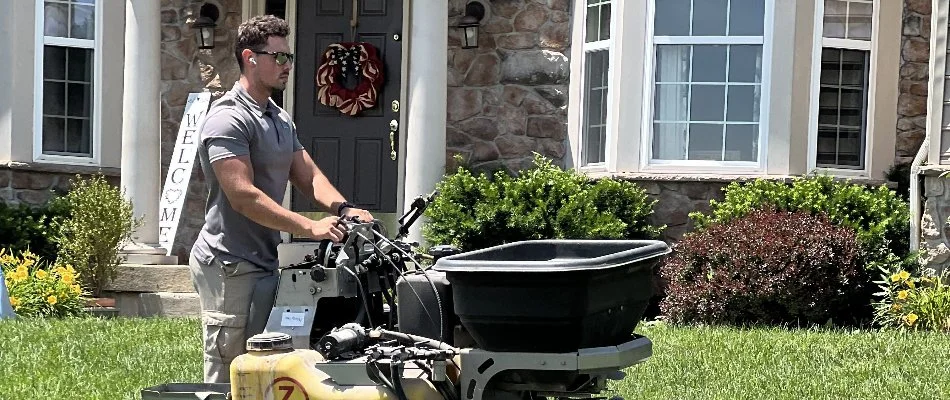 Lawn care employee spreading fertilizer in the spring on property in Telford, PA.