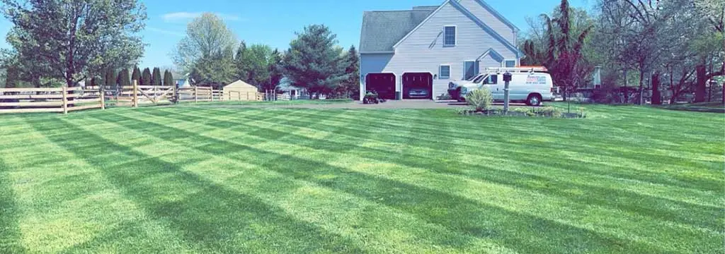 Bright green lawn grass with a service van and home in the background near Souderton, PA.