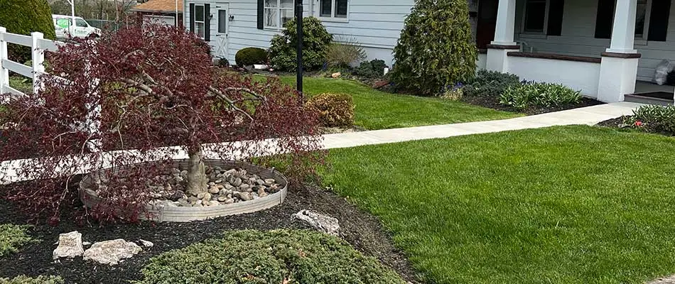 Home with a lush green lawn and beautiful landscaping near a white fence in Perkasie, PA.