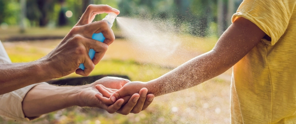 Mother applying tick repellant spray to child in Lansdale, PA.